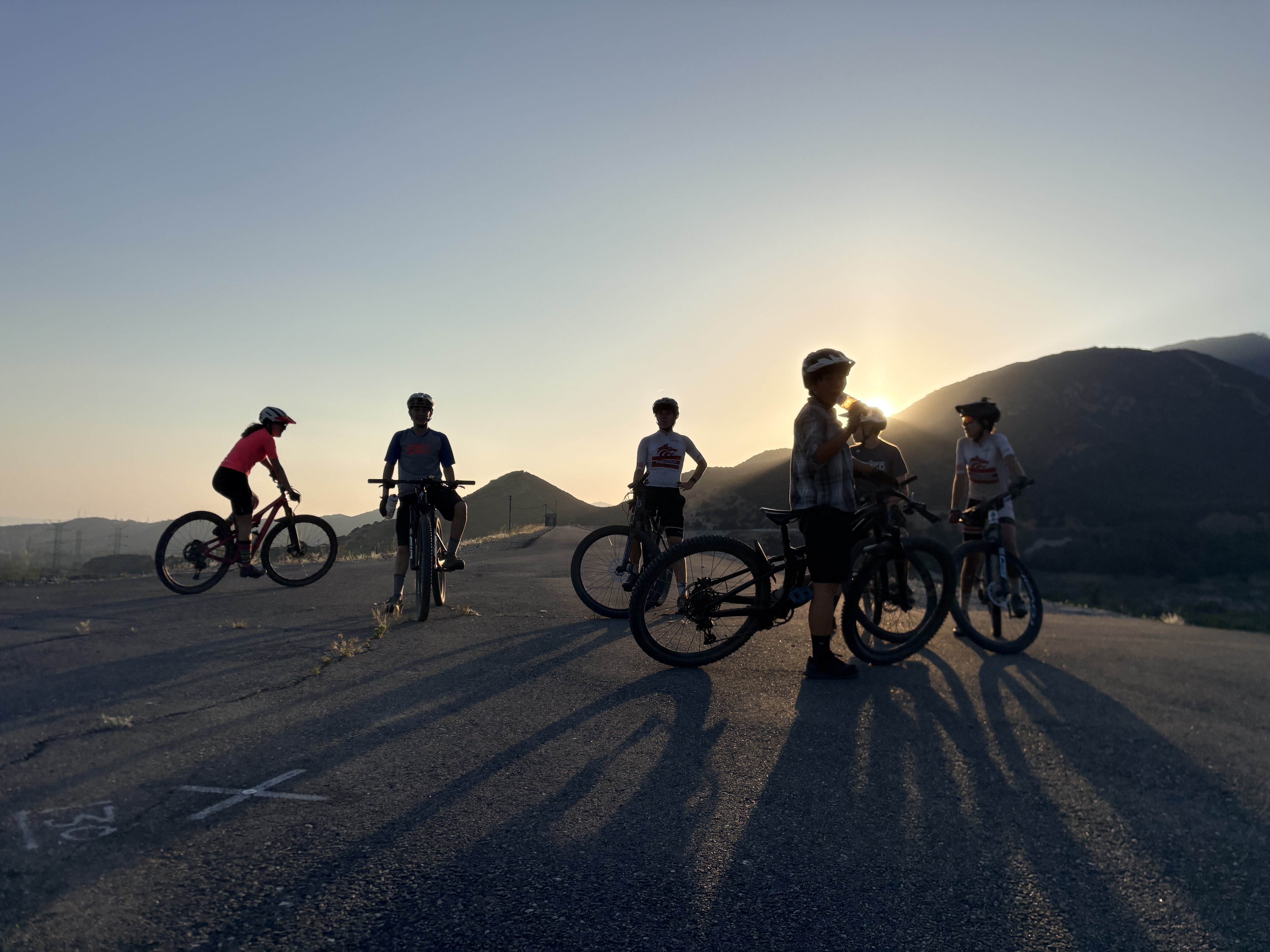 Wolfpack riders stretching in a circle at dusk practice with the San Gabriel mountains behind